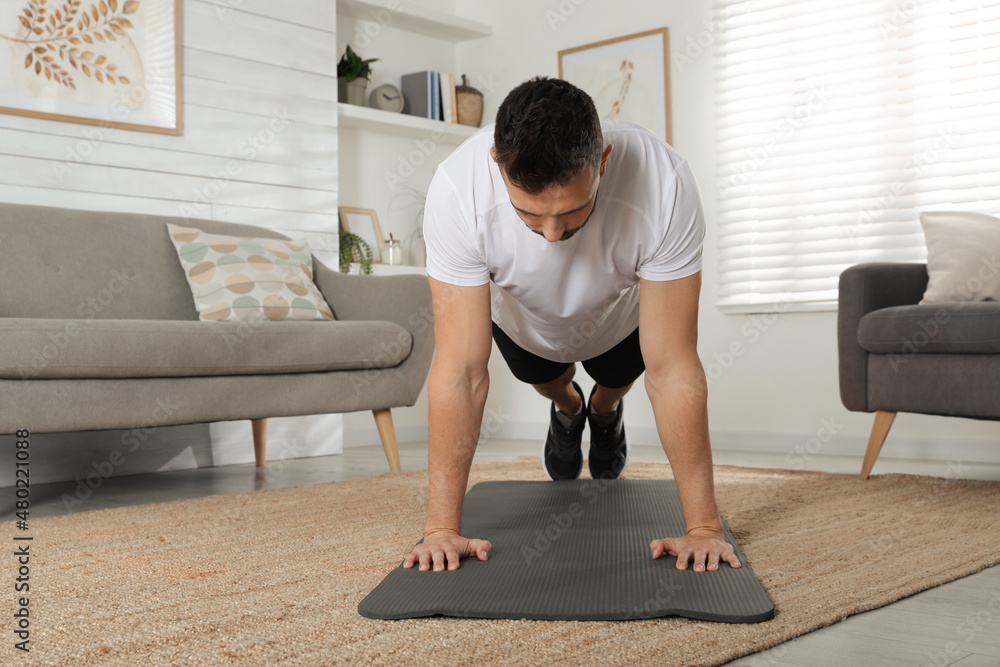 Sticker Handsome man doing plank exercise on yoga mat at home