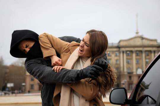 Woman defending herself from attacker near car outdoors