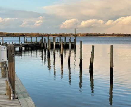 Empty bayside boat dock on calm water with soft, dramatic sky © Andrea DiSavino
