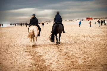 Foto auf Acrylglas January 1, 2022, Katwijk aan Zee, The Netherlands relaxed people walking and ride horses on the beach © zivko.trikic