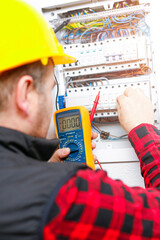The electrician measures the electric current on the wires and the fuse switch. Multimeter in the...