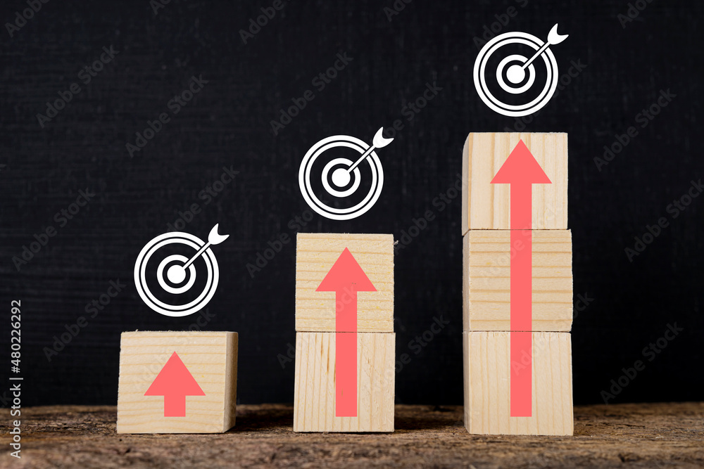 Poster wooden blocks stacked in steps with red arrows on the table.