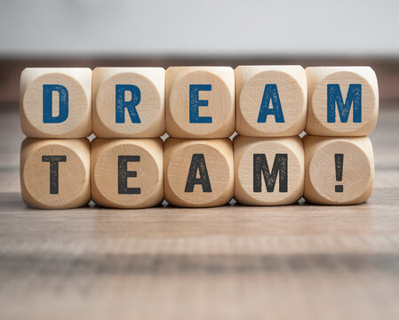 Cubes, dice or blocks with dreamteam or dream team on wooden background