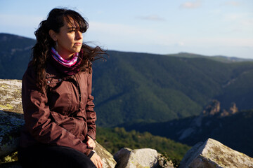 Naklejka premium Serious woman on the hill of a mountain looking the landscape