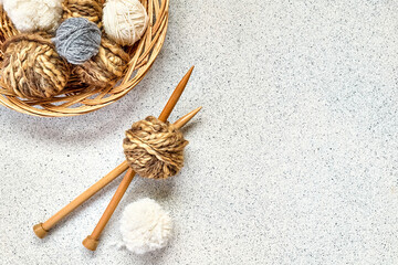Balls of wool yarn and wooden knitting needles on the table. Hobby craft background with space for text. Concept of knitting, needlework.