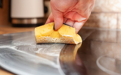 A young woman is cleaning an induction electric hob. Cleaning in the kitchen. Electric oven...