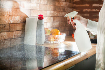 A young woman is cleaning an induction electric hob. Cleaning in the kitchen. Electric oven...