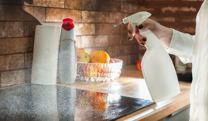 A young woman is cleaning an induction electric hob. Cleaning in the kitchen. Electric oven...