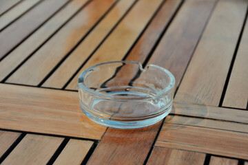 Empty glass ashtray on a wooden table, close-up
