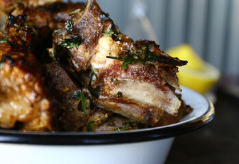 grilled or roasted pieces of fat well done pork meat with herbs in rustic style on white iron dish