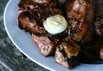 roasted grilled pieces of fat pork meat with onion rustic style on white plate