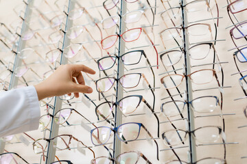 low angle view of cropped oculist taking eyeglasses in optics shop.