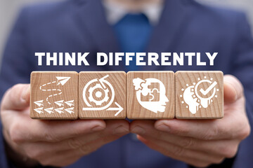 Think differently business concept. Man holding wooden cubes with icons and think differently text. Being different. Be unique and creative.