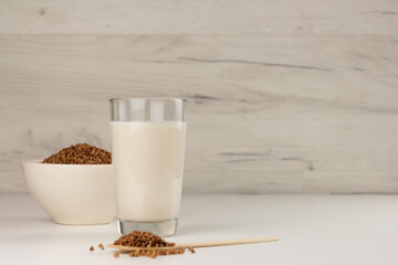 Dairy free buckwheat milk in a glass and buckwheat grains in a bowl