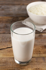 Dairy free rice milk in glasses and rice grains in a bowl on wooden background