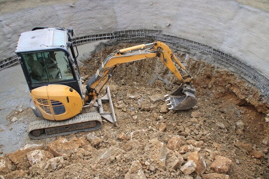 Kleiner Bagger baggert in einer Baugrube