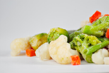 A mixture of frozen vegetables in a pile. Preparation for a dish on a white background.