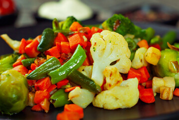 Mix of vegetables close up. Salad of various chopped vegetables. Roasted cabbage, carrots, broccoli, peas on a plate.