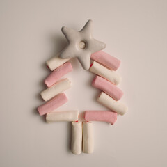 Christmas tree made from pink and white marshmallows and decorated with white gingerbread star on a white background, top view, flat lay, copy space.