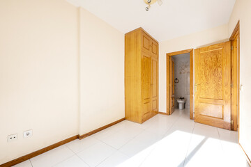 Empty room with own bathroom and built-in pine wood wardrobe and porcelain floors