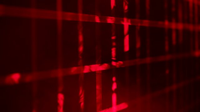 Red laser beams from stage lights create a checkered pattern in a dark studio with thick clouds of smoke. Lighting equipment. Lighting effects. Show of stage holograms. Close up. Slow motion.
