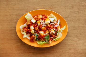 Delicious Golden Sauce Chicken garnished with onion and chili on wood table background top view