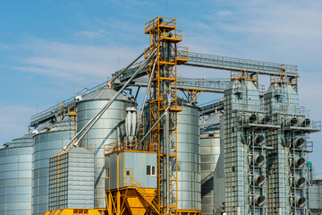 silver silos on agro manufacturing plant for processing drying cleaning and storage of agricultural products, flour, cereals and grain. Large iron barrels of grain. Granary elevator © Pokoman