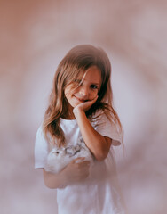 Close-up portrait of beautiful blond toddler girl hugging her favorite handmade toy, knitted cat.