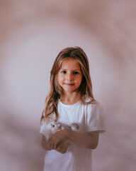 Close-up portrait of beautiful blond toddler girl hugging her favorite handmade toy, knitted cat.