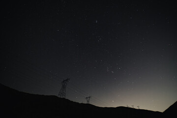 Astronomy photo of the bright galactic cloud of the Milky Way stretches across the night sky over a remote mountainous and forested landscape in Yellowstone National Park