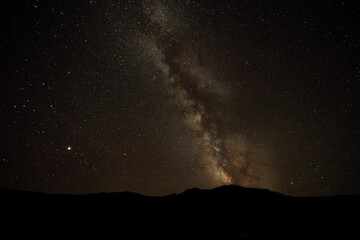 Astronomy photo of the bright galactic cloud of the Milky Way stretches across the night sky over a...