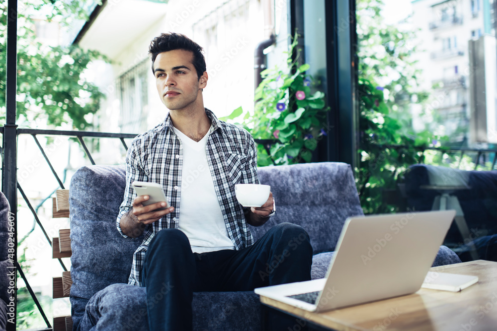 Poster man with tea cup and cellphone device thinking about content idea for sharing via laptop computer, p