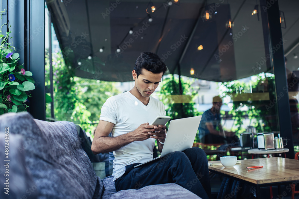 Poster millennial male generation z with laptop computer using modern cellular device for making online boo