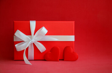Red gift box with white bow and hearts on red background with copy space. Gift for Valentine's Day, March 8, mother's day, birthday.