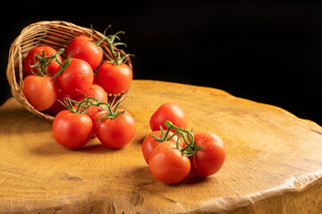 Tomatoes, beautiful tomatoes falling from a straw basket on rustic wood, selective focus.