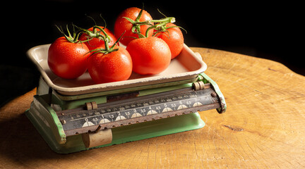 Tomatoes, beautiful tomatoes placed on an old weighing scale, over rustic wood, selective focus.