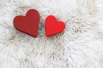 There are two paper hearts on white faux fur. Space for text. Copy space