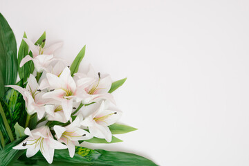 Creative layout made of white Lilies and leaves. Flat lay. Nature concept. Floral Greeting card. Colorful spring flower background, space for text. Nature Trendy Decorative Design.