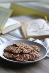 Plate of healthy gluten free cookies, open books and reading glasses on the table. Selective focus.