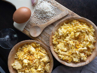 Top view of two plates of Nelga Rice along with various ingredients and a glass of wine.