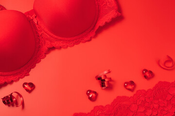 Red Valentine's Day background with beautiful female lacy panties, bra and hearts. Sexy underwear. Free space for text, copy space. Postcard, greeting card design. Love, celebration concept.