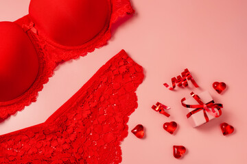 Pink Valentine's Day background with beautiful female lacy panties, bra, hearts and gift box. Sexy underwear. Free space for text, copy space. Postcard, greeting card design. Love, celebration concept