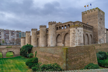 Fototapeta premium Exterior view of Aljaferia Palace in Zaragoza, Spain. Traditional fortified medieval castle surrounded by a moat with a green lawn