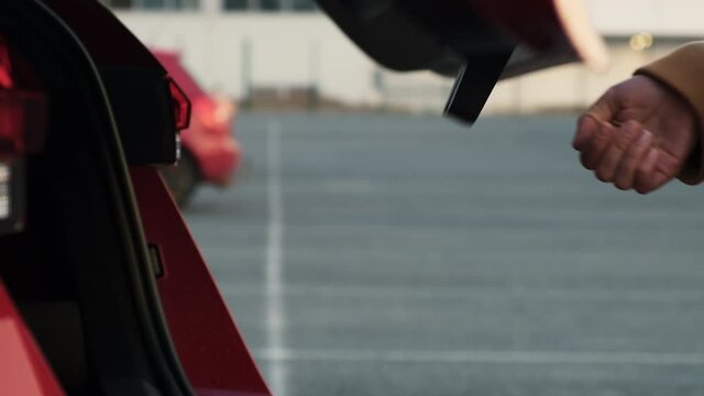 A woman opens the trunk and takes out a suitcase. Business trip concept.