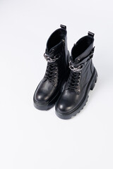 Women's shoes on a white background. Close-up of women's black leather boots with buckles on a white background. Shoes for the city. Concept for 2022 fashion, design and footwear.