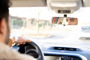 Caucasian or eastern ethnicity man casually dressed with hands holding driving wheel, looking in...