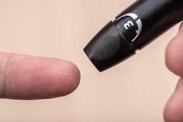 A person is about to pierce the skin of a finger with a lancet to measure blood sugar.