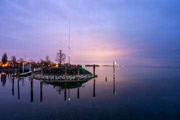 Fototapeta na wymiar Der beruhigende Sonnenuntergang im Hafen von Immenstaad am Bodensee zeigt die wunderschönen Farben der bunten Wolken im Wasser