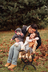 Fototapeta premium A single father with two daughters sitting on a bench in the park 