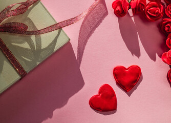 Two love heart, gift and red roses on a pink background in backlit.